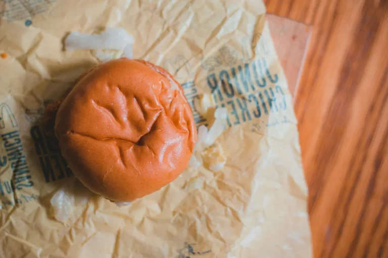 Best chicken sandwich menus in America - A close-up of a crispy chicken sandwich on a wooden table with pickles and sauce