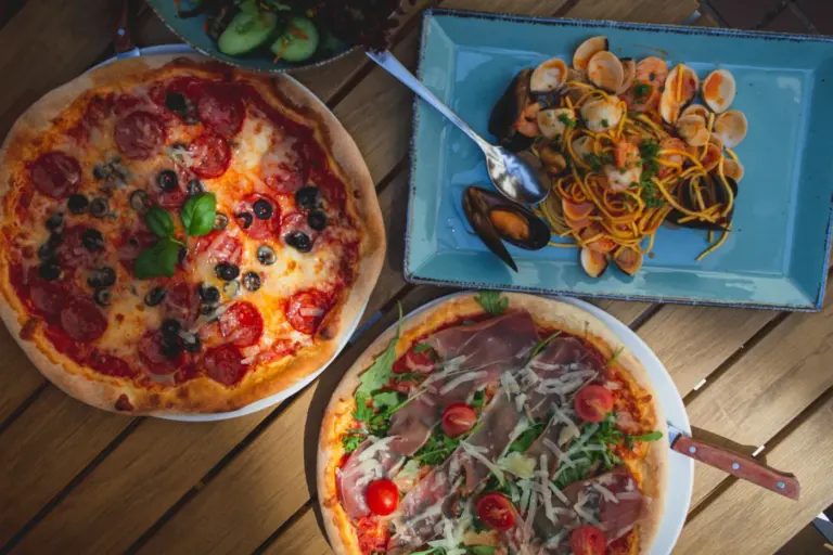 Italian Restaurant Menu Guide for Quick Lunch in America - Italian lunch spread including pizza slice, pasta bowl, and panini on a wooden ta